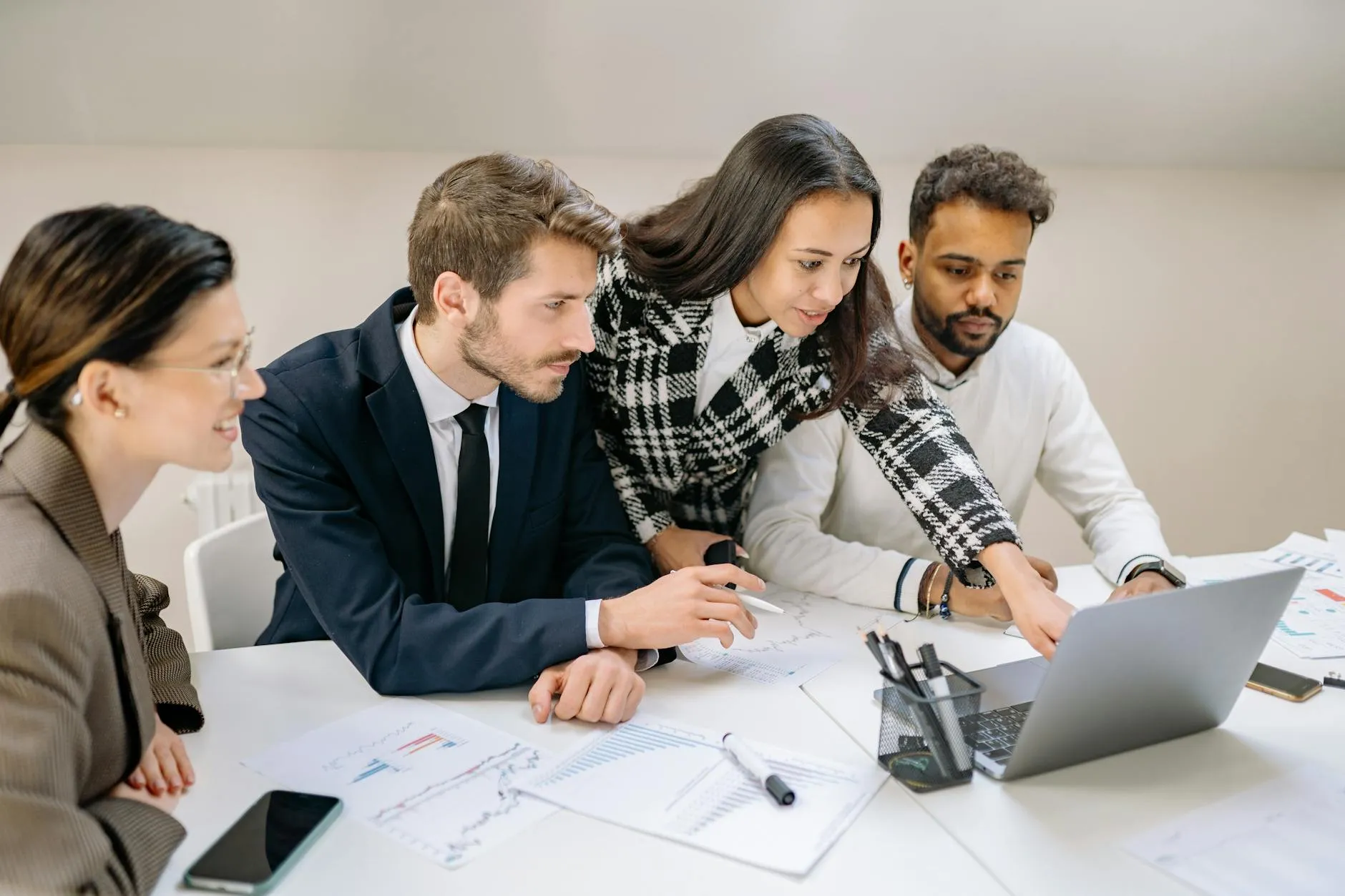 A business team discussing vendor options around a laptop in a meeting room